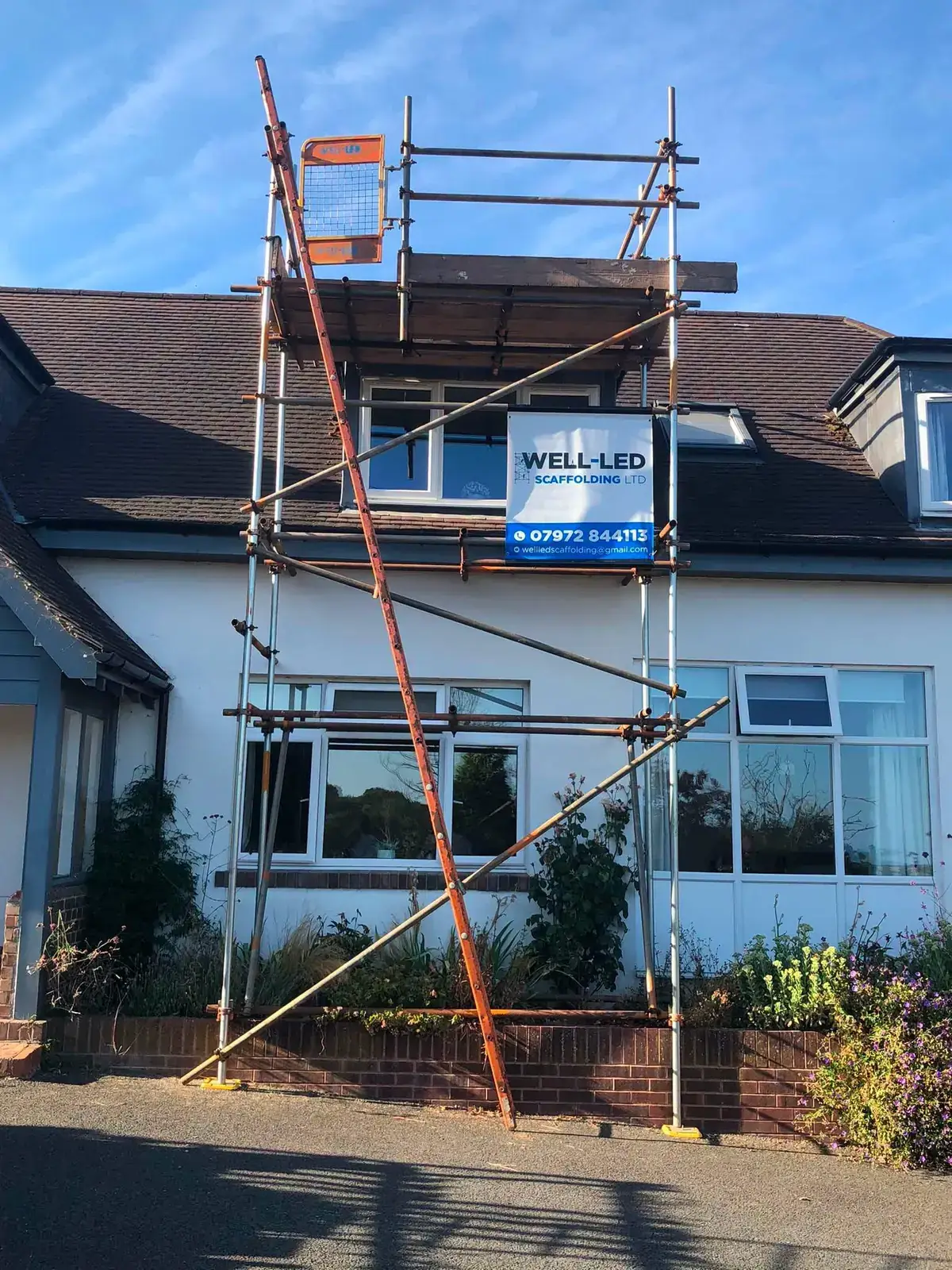 Dormer roof scaffolding erected on a detached bungalow in Exeter, Devon, with the Well-Led Scaffolding banner fixed to the lift.