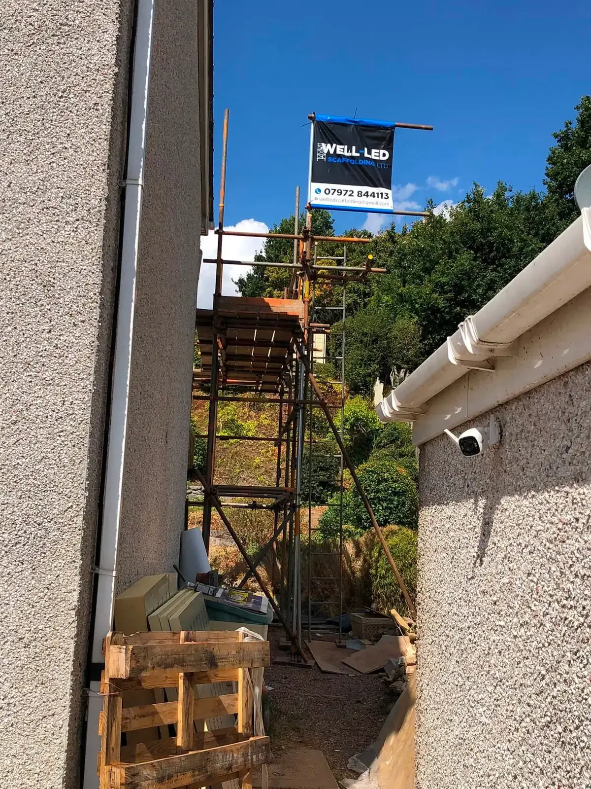 Narrow-access tower scaffold built into a tight side alley between two houses in Exeter, Devon.